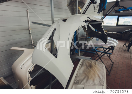 Auto bumper part is installed on the racks after painting in car repair shop. Auto bumper part is installed on the racks after painting in car repair shop. 70732573