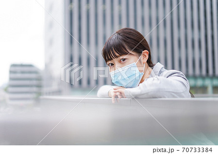 マスクをしてビジネス街を歩く若いビジネスウーマン マスクをしてビジネス街を歩く若いビジネスウーマン 70733384