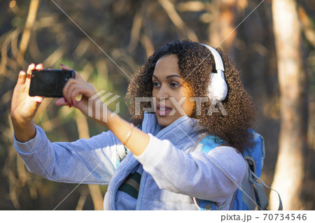 African American woman in the forest taking a photo on a smartphone. 70734546