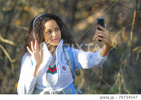 African American woman in the forest taking a selfie on a smartphone. 70734547