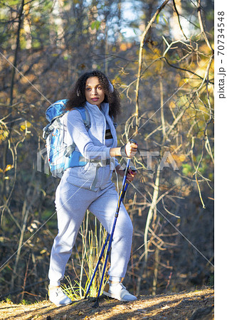 Vertical photo of a smiling African American woman walking through the forest. 70734548