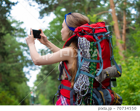 Woman taking a photo with smartphone while walking in the forest. 70734550