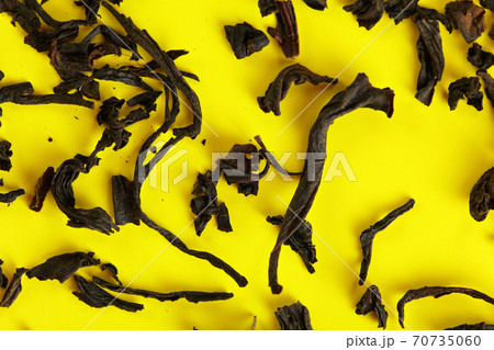 Dry black loose tea leaves on yellow board, closeup detail from above Dry black loose tea leaves on yellow board, closeup detail from above 70735060