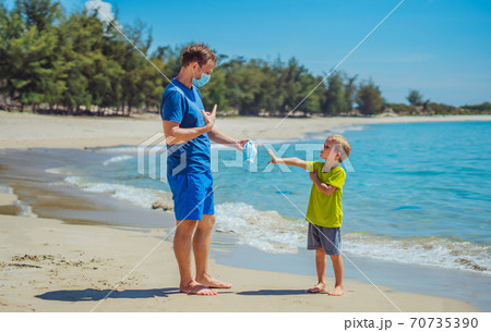 Normal reality COVID pandemic. Father ask boy put on mask protect coronavirus, son refuses does not want to constantly wear it everywhere, get tired of mask, walk nature sea beach forest park sun day Normal reality COVID pandemic. Father ask boy put on mask protect coronavirus, son refuses does not want to constantly wear it everywhere, get tired of mask, walk nature sea beach forest park sun day 70735390
