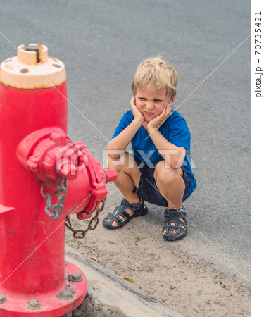 Study everyday knowledge skills. Blond freckled face 5 year boy facial expression blue COVID face mask think about fireman fighters engine looking on red fire hydrant. Children safety people concept 70735421