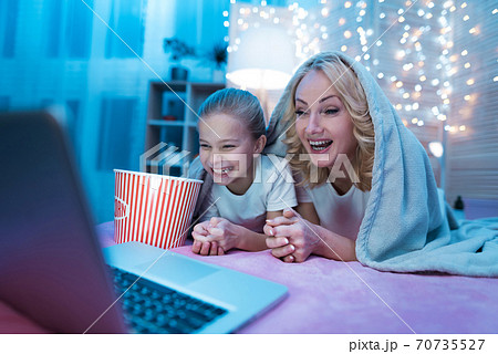 Grandmother and granddaughter are watching movie. 70735527