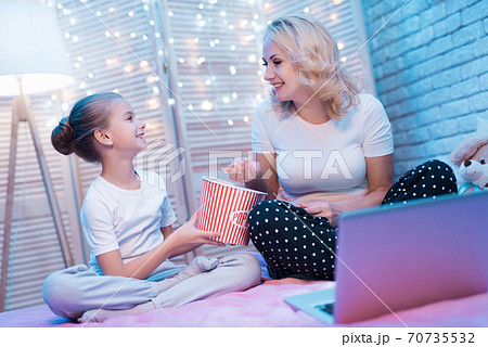 Grandmother and granddaughter eat popcorn. 70735532