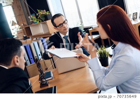 A lawyer in a suit gives the couple a document. 70735649
