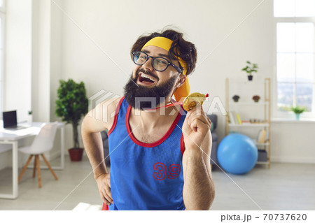 Portrait of a crazy emotional joyful athlete man holding a medal in his hand and flaunting it. Portrait of a crazy emotional joyful athlete man holding a medal in his hand and flaunting it. 70737620
