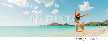 Christmas fun travel vacation bikini girl jumping of joy on Caribbean beach santa hat woman happy panoramic banner landscape holiday Christmas fun travel vacation bikini girl jumping of joy on Caribbean beach santa hat woman happy panoramic banner landscape holiday 70742898