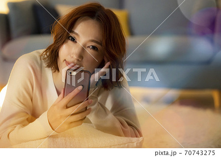 夜のリビングでスマホを見る女性 夜のリビングでスマホを見る女性 70743275
