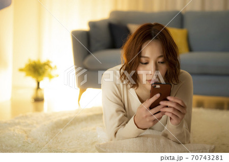夜のリビングでスマホを見る女性 夜のリビングでスマホを見る女性 70743281