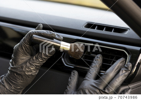 Worker cleaning automobile air conditioner vent grill with brush, closeup. Car wash service Worker cleaning automobile air conditioner vent grill with brush, closeup. Car wash service 70743986