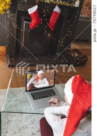 Woman in Santa hat having a video chat with another woman on laptop at home 70748027