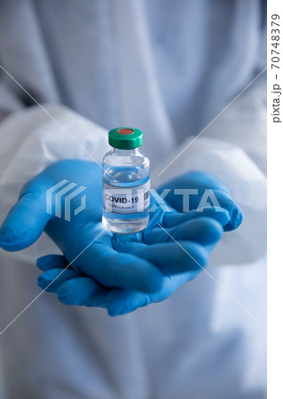 Close up of Health worker wearing protective gloves holding a vial bottle with Covid-19 text Close up of Health worker wearing protective gloves holding a vial bottle with Covid-19 text 70748379