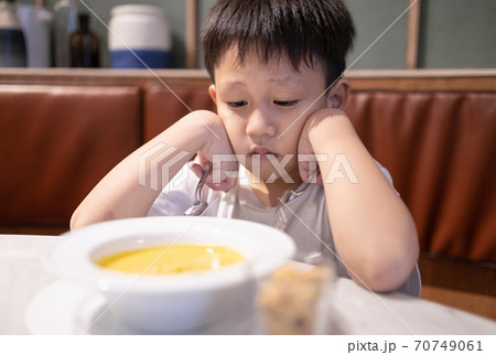Depressed asian kid boy with anorexia,don't have appetite,child kindergarten bored with food or boredom,refusing to eat vegetable soup,unpalatable,tired of food,nutrition and eating disorder concept 70749061