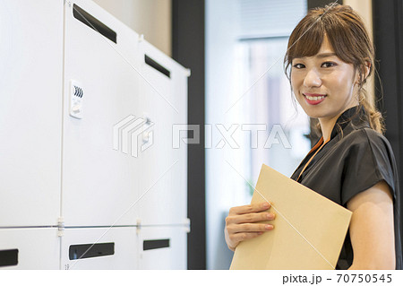 書類をポストに投函しようとしているビジネスパーソン 書類をポストに投函しようとしているビジネスパーソン 70750545