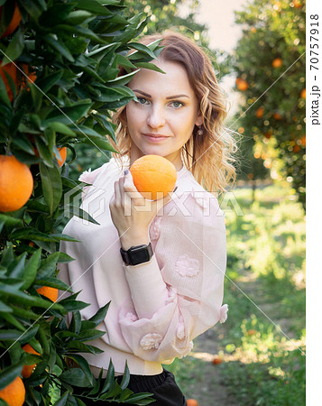 Young pretty woman smelling orange fruit in the garden 70757918