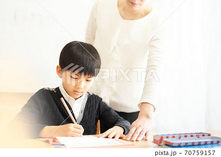 勉強している小学生と教えている女性 勉強している小学生と教えている女性 70759157