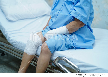 Asian senior or elderly old lady woman patient accident at arm and knee with bandage on bed in nursing hospital ward. 70759772