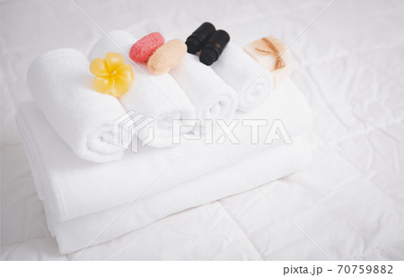 Spa object with white towels,organic soap,luffa scrub, and plumerai flower candle on clean white bedding. Spa object with white towels,organic soap,luffa scrub, and plumerai flower candle on clean white bedding. 70759882