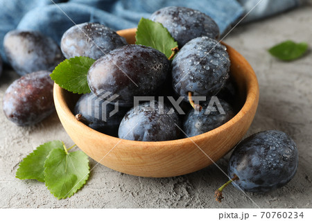 Napkin and bowl with plums on gray background 70760234
