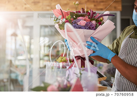 Floral artist keeping a flower bouquet above a paper package 70760958