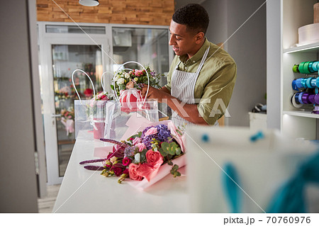 Florist moving a pot of roses into a carrier bag Florist moving a pot of roses into a carrier bag 70760976