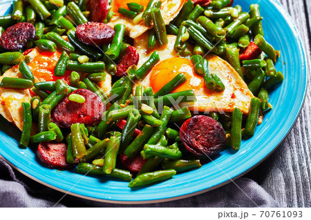 Green beans fried eggs and chorizo on a blue plate 70761093