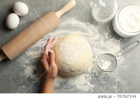 Female hand hold dough on gray background with ingredients for baking Female hand hold dough on gray background with ingredients for baking 70762534