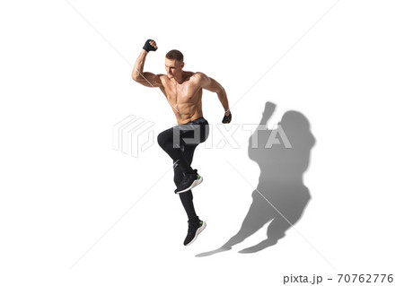 Beautiful young male athlete practicing on white studio background with shadows 70762776