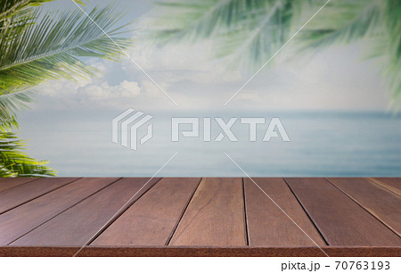 Brown wooden planks with blur beach sea sky on background and  palm leaves on foreground,summer concepts 70763193