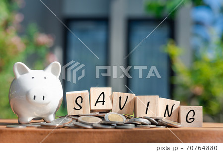 Piggy bank money coins and saving word on wooden cubics on wood table with nature house background Piggy bank money coins and saving word on wooden cubics on wood table with nature house background 70764880