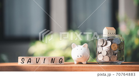 Saving money concepts  with coins,house,wood cubics and piggy bank model on nature green grass background 70764883