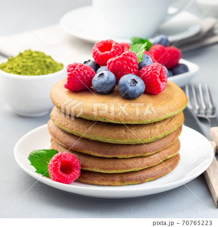 Matcha pancakes served blueberry and raspberry on white plate, square format 70765223