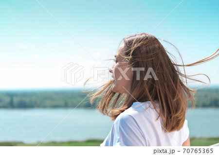 beautiful woman with hair blown by wind looking at landscape beautiful woman with hair blown by wind looking at landscape 70765365