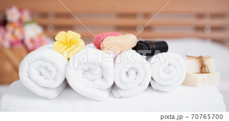 Spa wellness concept with white towels,candle,milk soap,beautiful frangipani  flowers in bamboo wooden basket  on modern white bedroom 70765700