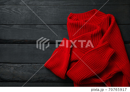 Red knitted sweater on wooden background, top view Red knitted sweater on wooden background, top view 70765917