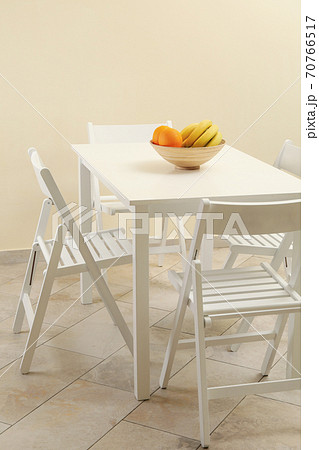 White table with fruits and folding chairs in kitchen room 70766517