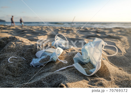 Medical face mask discarded trash on sandy beach,covid19 pandemic pollution  70769372