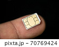 Isolated nano sim card on human finger over black background,hi tech smartphone 70769424