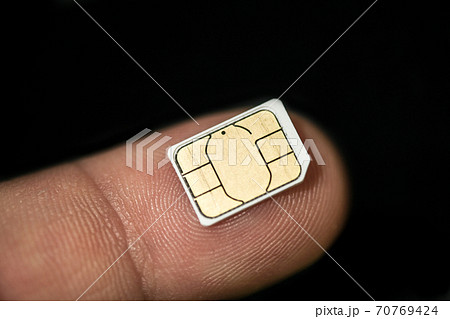 Isolated nano sim card on human finger over black background,hi tech smartphone 70769424