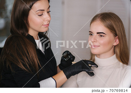 Brow master applies henna on eyebrows for beautiful blond hair woman Brow master applies henna on eyebrows for beautiful blond hair woman 70769814