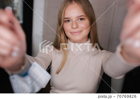 Beautiful blond hair woman making selfie in medical mask on hand. Woman in beauty studio Beautiful blond hair woman making selfie in medical mask on hand. Woman in beauty studio 70769826