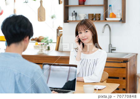 テレワークをする夫とスマホで話をする妻 70770848