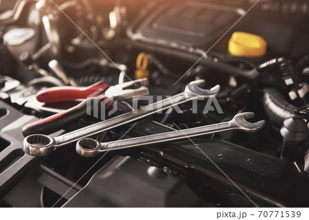 Mechanic hand checking and fixing a broken car in car service garage Mechanic hand checking and fixing a broken car in car service garage 70771539