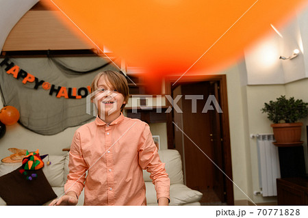 a boy is having fun and playing with orange and black Halloween baloons 70771828