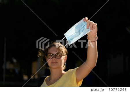 Happy positive girl with glasses, young beautiful woman takes off protective medical mask from face and smiling Happy positive girl with glasses, young beautiful woman takes off protective medical mask from face and smiling 70772243