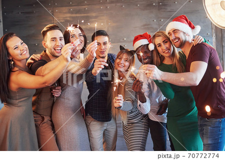 Party with friends. Group of cheerful young people carrying sparklers and champagne flutes Party with friends. Group of cheerful young people carrying sparklers and champagne flutes 70772774