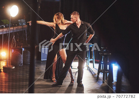 Skillful dancers performing in the dark room under the light 70772782